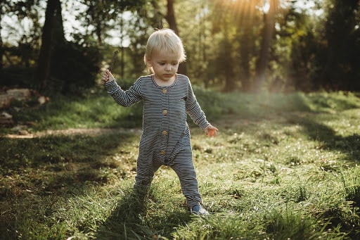 Baby in romper standing in meadow